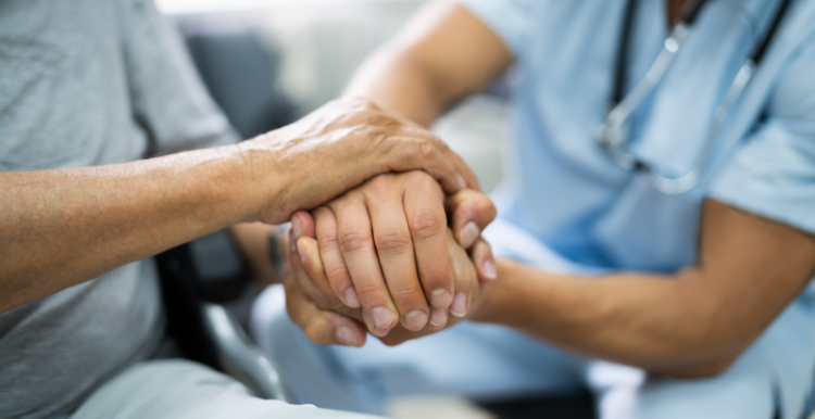 A healthcare professional holding a patient's hand.