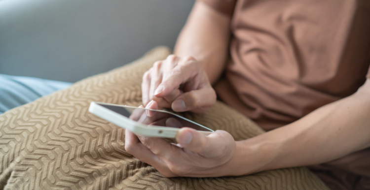Person sat on a sofa looking at a mobile phone.