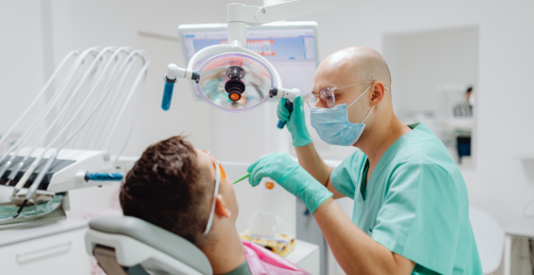 A dentist tending to a patient in a reclined dentist chair.