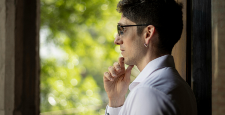 A person standing looking out of the window - their gaze looks thoughtful