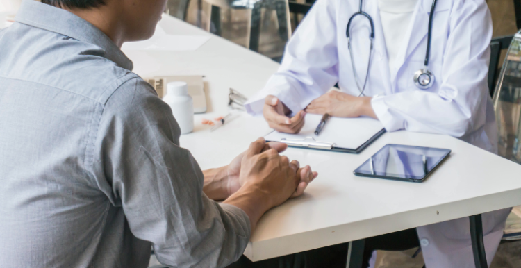 2 people sat at a table. One is wearing a stethoscope.