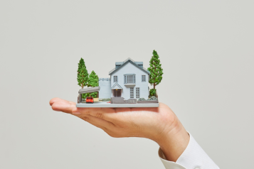 A hand is holding a model of a house