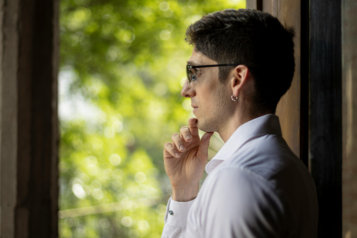 A person standing looking out of the window - their gaze looks thoughtful