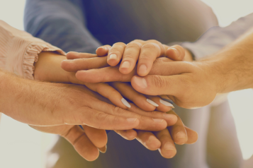 Several hands coming together - placed on top of each other