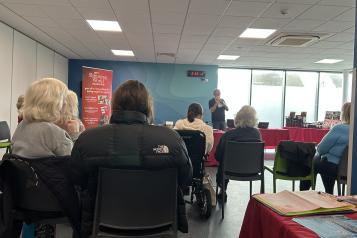 Photo of one of our engagements at a Slimming world meeting. The speaker can be seen at the front and then we can see the backs of everyone else as they are sitting facing him in the room.