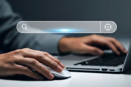 Background of the photo shows a persons hands on a laptop keyboard. In the forgrpund is a search bar with an AI graphic to the right.