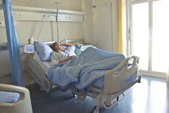 Photo of a person laying in a hospital bed looking out of the window