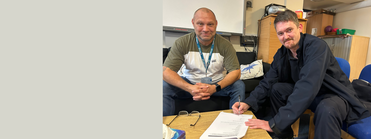 A man completing a survey at one of our engagement events. He is sat down with one of our volunteers