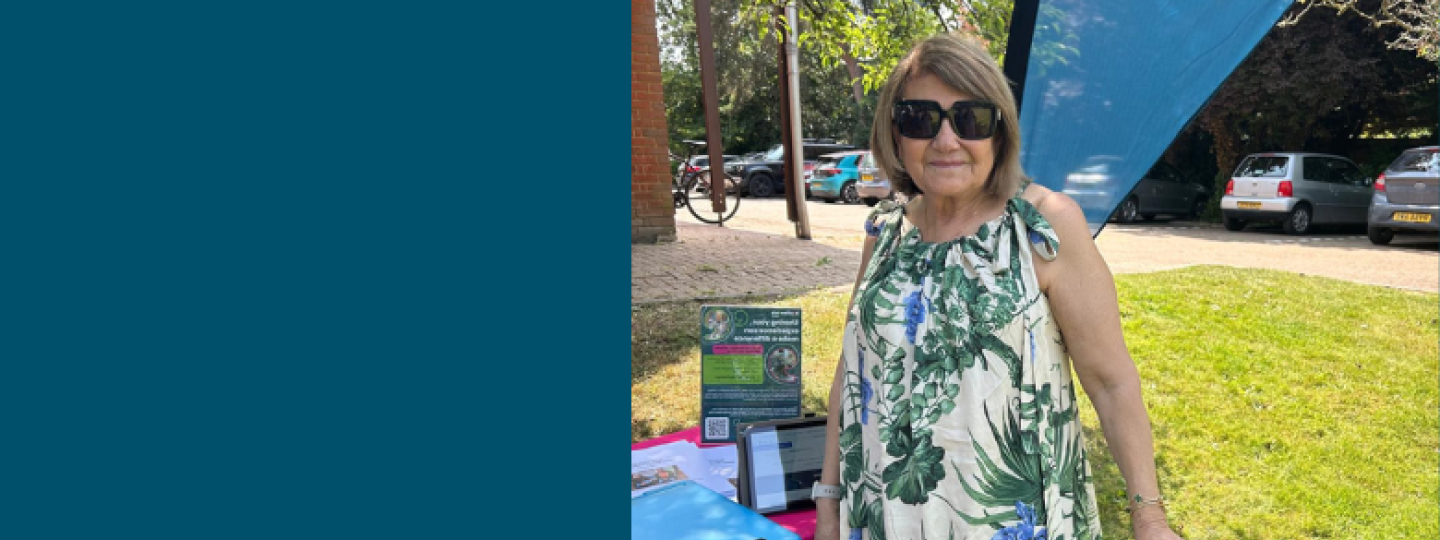 A woman stood outside next to our Healthwatch Surrey tables. The Healthwatch banner can be seen in the background