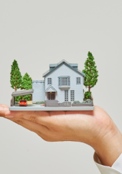 A hand is holding a model of a house