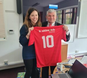 Hysen from Red and Black Roots Football, presenting Hannah, our Volunteer Coordinator with a new Healthwatch Surrey football shirt